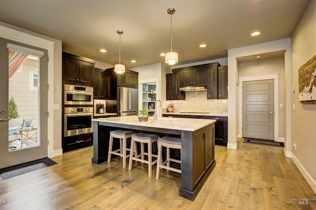 kitchen with dark brown cabinetry, a sink, gas stovetop, stainless steel refrigerator, and decorative backsplash