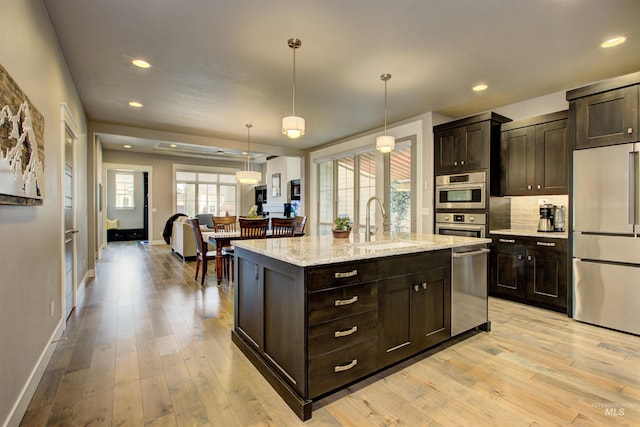 kitchen featuring appliances with stainless steel finishes, light wood-type flooring, a sink, and dark brown cabinetry