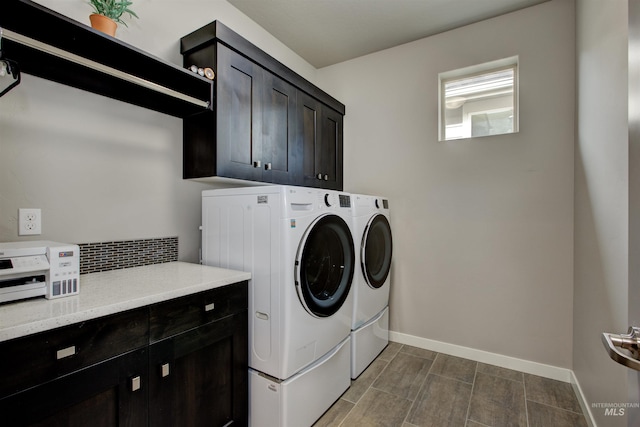 washroom featuring washer and clothes dryer, cabinet space, and baseboards