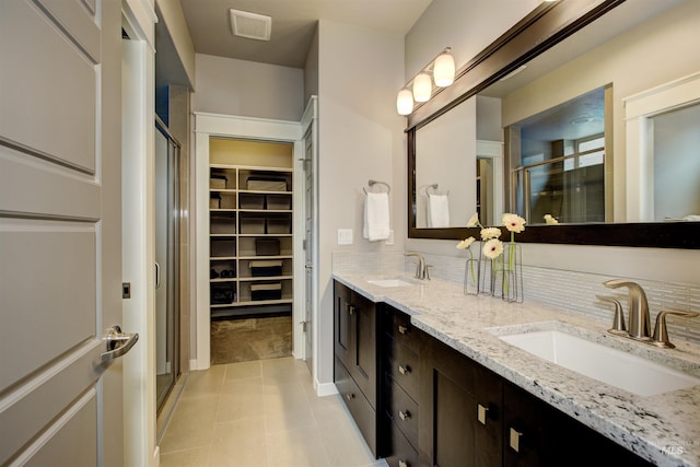 bathroom with double vanity, a sink, a walk in closet, and a shower stall