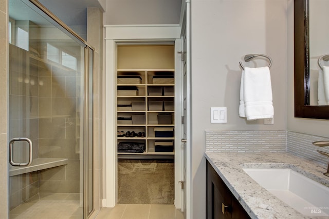 bathroom with a walk in closet, a shower stall, vanity, and tile patterned floors