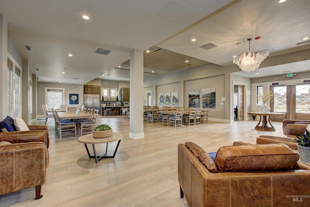 living room with visible vents, light wood-style flooring, and an inviting chandelier