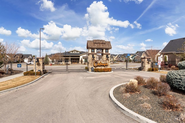 view of road featuring curbs, a gated entry, a gate, and a residential view