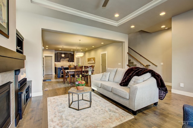 living area featuring a tile fireplace, recessed lighting, a ceiling fan, baseboards, and wood-type flooring