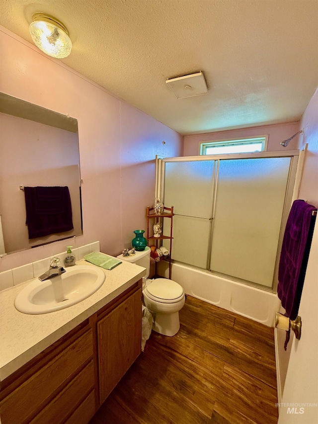 103 Beech St, Nezperce, ID 83543 - bathroom featuring a textured ceiling, wood finished floors, vanity, bath / shower combo with glass door, and toilet