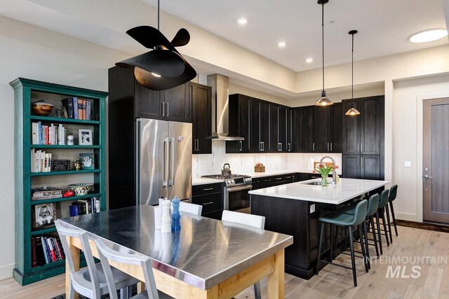 880 W River St, Boise, ID 83702 - kitchen featuring wall chimney range hood, appliances with stainless steel finishes, a center island with sink, a sink, and light countertops