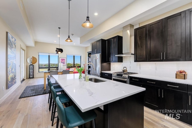 880 W River St, Boise, ID 83702 - kitchen with a center island with sink, wall chimney exhaust hood, a sink, appliances with stainless steel finishes, and backsplash