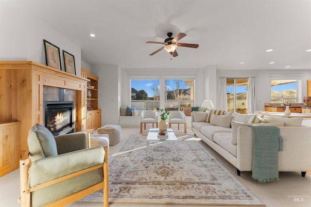 carpeted living room featuring ceiling fan, a healthy amount of sunlight, and a fireplace