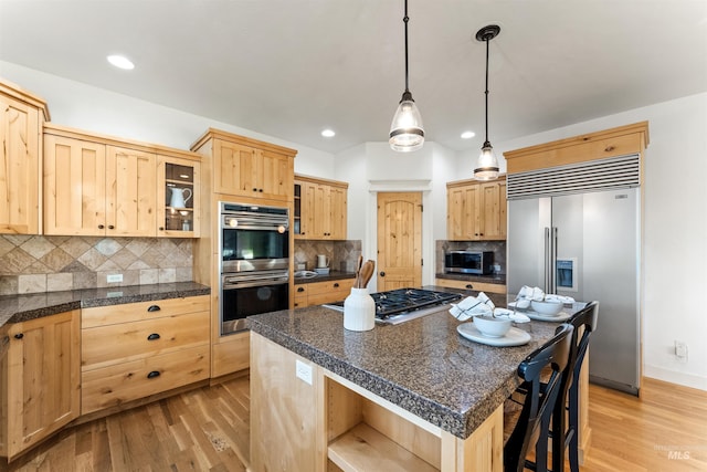 kitchen featuring light brown cabinets, stainless steel appliances, backsplash, and a center island