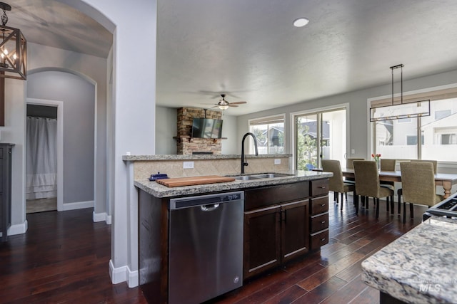 kitchen featuring dishwasher, a sink, ceiling fan, arched walkways, and dark wood-type flooring
