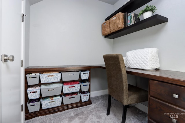 carpeted office featuring built in desk and baseboards