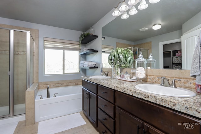 bathroom with a shower stall, a garden tub, tile patterned flooring, double vanity, and a walk in closet