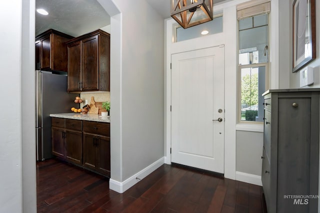 foyer featuring baseboards, arched walkways, and dark wood-style floors