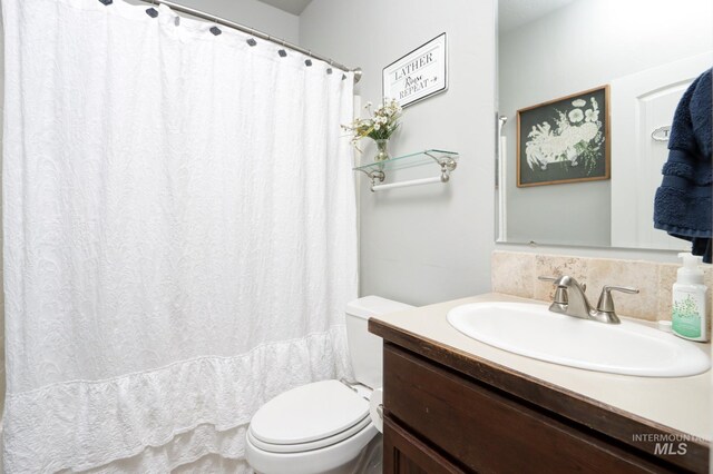 bathroom with toilet, vanity, and backsplash