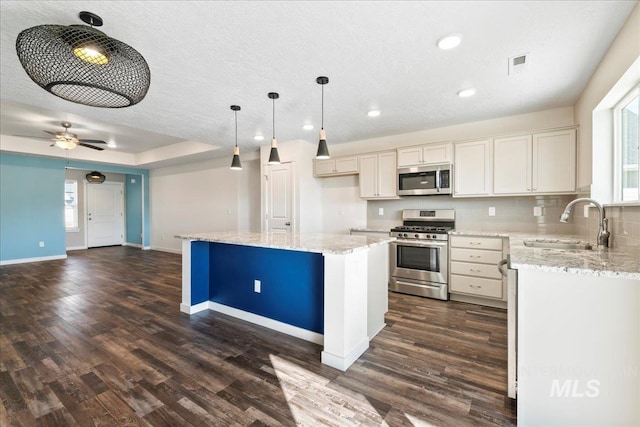 kitchen featuring sink, decorative light fixtures, a center island, dark hardwood / wood-style flooring, and stainless steel appliances