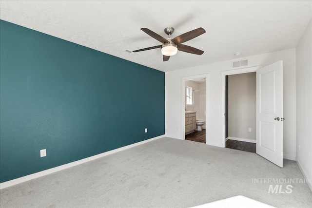 unfurnished bedroom with ensuite bath, ceiling fan, and carpet