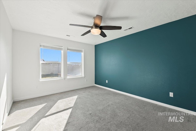 unfurnished room featuring light carpet, ceiling fan, and a textured ceiling