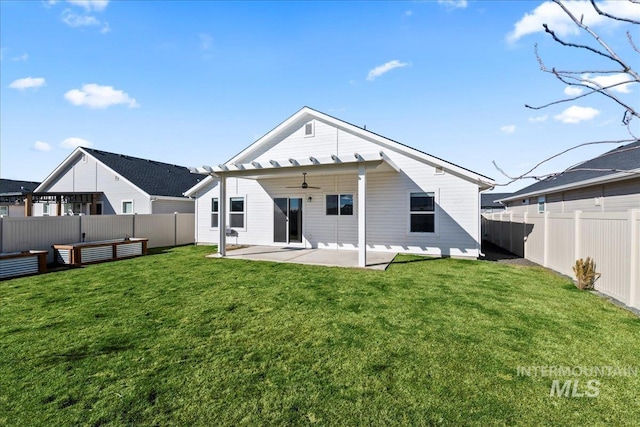 back of property with ceiling fan, a yard, and a patio