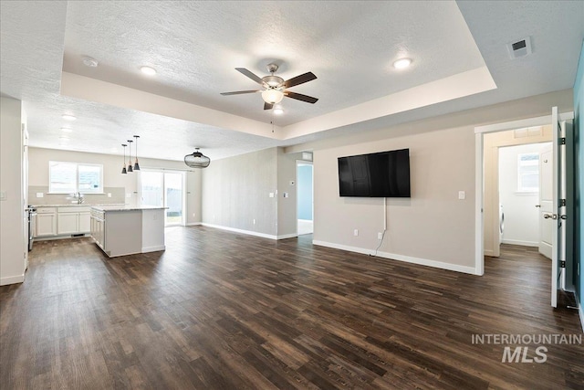 unfurnished living room featuring dark hardwood / wood-style floors, a raised ceiling, and a textured ceiling