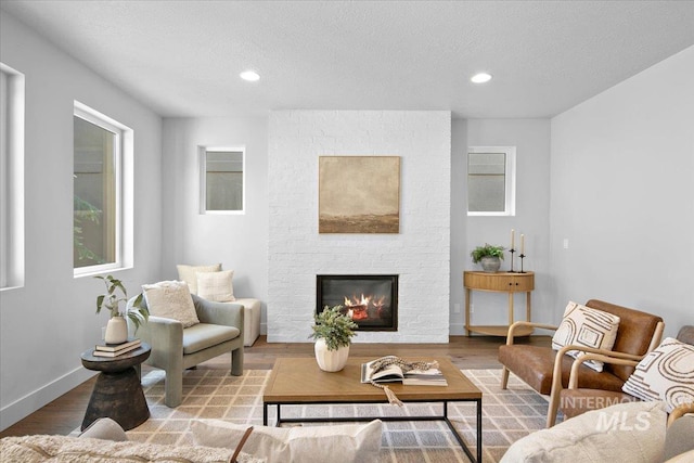 living room with a brick fireplace, recessed lighting, wood finished floors, and baseboards