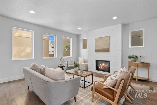 living room with baseboards, recessed lighting, a fireplace, hardwood / wood-style flooring, and a textured ceiling