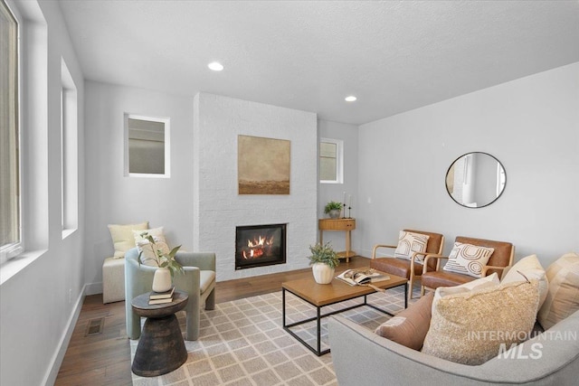 living room featuring visible vents, a large fireplace, baseboards, recessed lighting, and wood finished floors