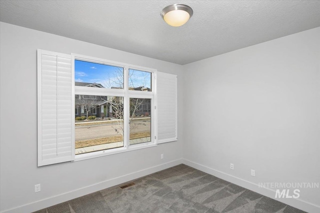 unfurnished room featuring visible vents, a textured ceiling, baseboards, and dark colored carpet