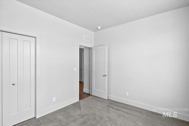 unfurnished bedroom featuring visible vents, baseboards, carpet flooring, a closet, and a textured ceiling