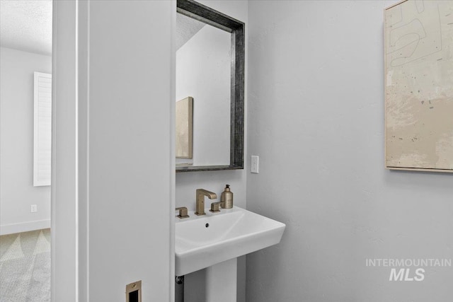 bathroom with a textured ceiling, baseboards, and a sink