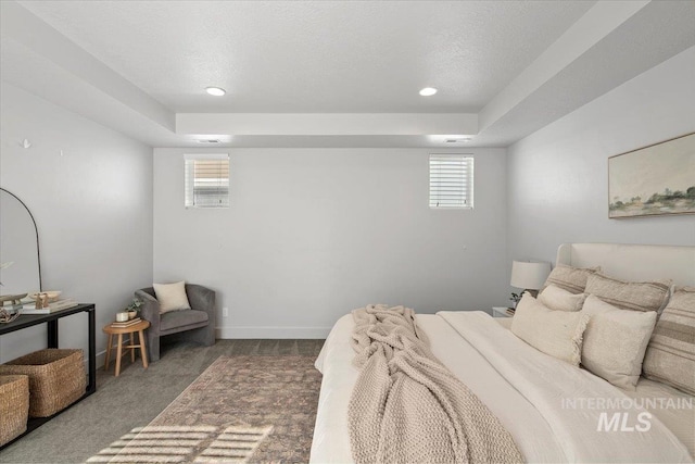 carpeted bedroom with a textured ceiling, baseboards, and a tray ceiling