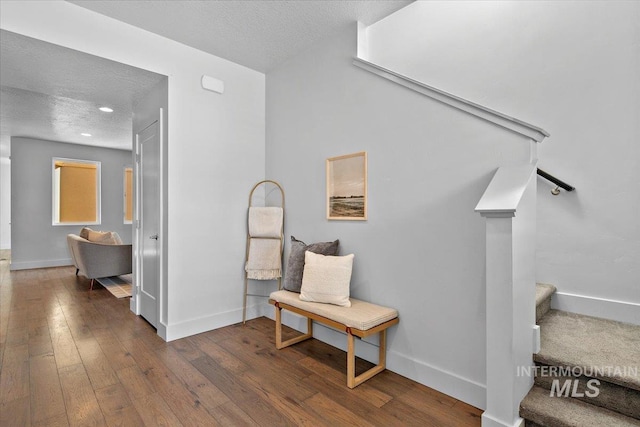 hall with hardwood / wood-style floors, baseboards, and a textured ceiling