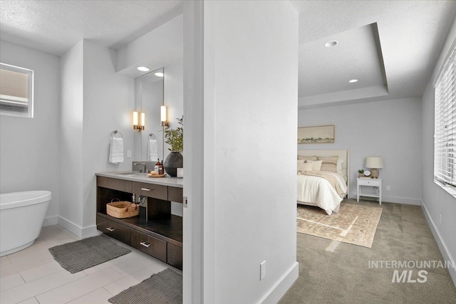 full bath with baseboards, vanity, a freestanding tub, a textured ceiling, and ensuite bath