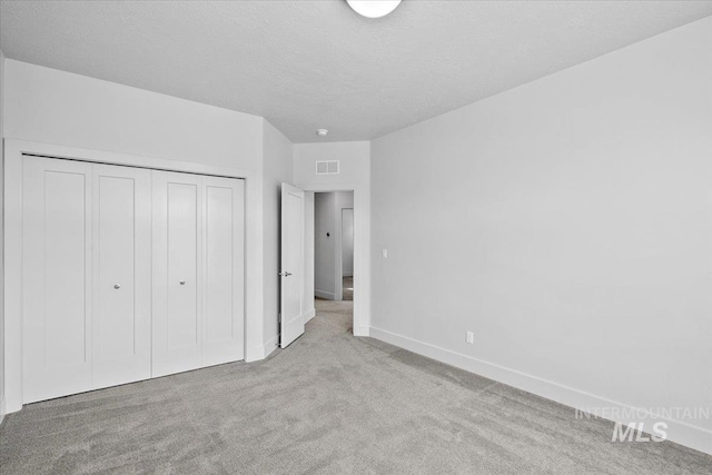 unfurnished bedroom with visible vents, baseboards, carpet, a closet, and a textured ceiling