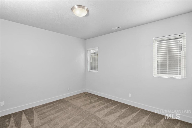 carpeted empty room featuring visible vents, a textured ceiling, and baseboards