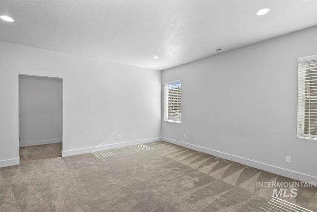 carpeted spare room featuring recessed lighting, baseboards, and a textured ceiling