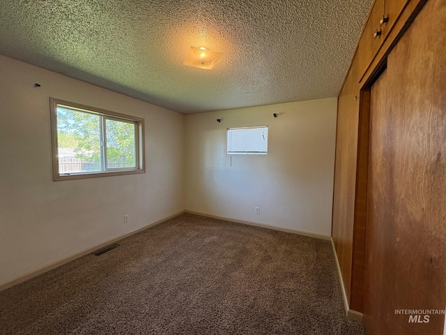 empty room featuring carpet flooring, a textured ceiling, and visible vents
