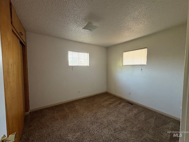 unfurnished bedroom with carpet flooring, a textured ceiling, baseboards, visible vents, and a closet