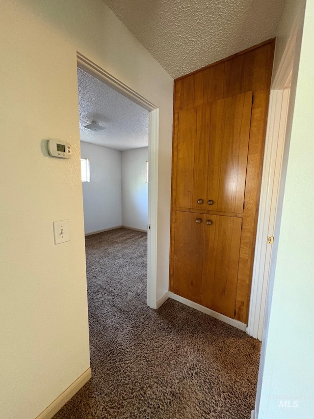 corridor featuring carpet flooring and a textured ceiling