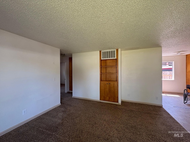 carpeted empty room featuring visible vents, a textured ceiling, and baseboards