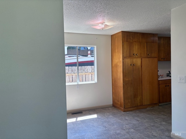 unfurnished bedroom featuring a textured ceiling, visible vents, and baseboards
