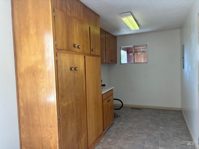 clothes washing area featuring baseboards and a textured ceiling