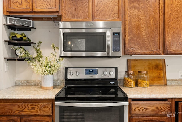 kitchen with light countertops, open shelves, brown cabinetry, and stainless steel appliances