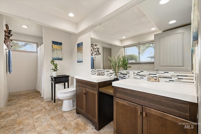 bathroom with vanity, tasteful backsplash, toilet, and a wealth of natural light
