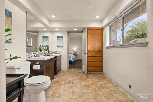bathroom featuring recessed lighting, plenty of natural light, toilet, and vanity