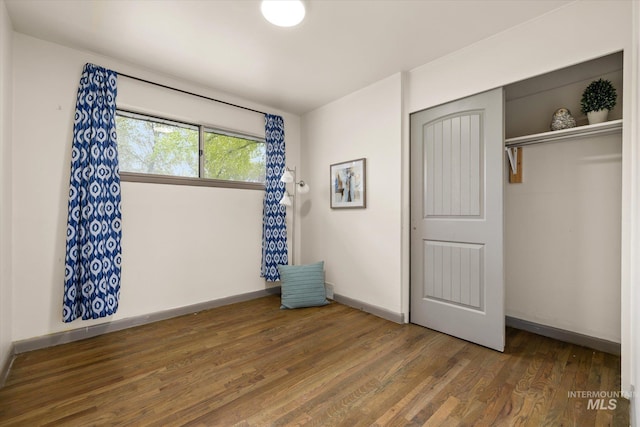unfurnished bedroom featuring a closet, baseboards, and wood finished floors