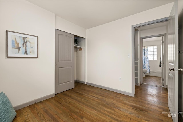 unfurnished bedroom with baseboards, wood finished floors, and a closet