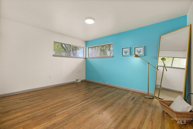 unfurnished room with visible vents, baseboards, and wood finished floors