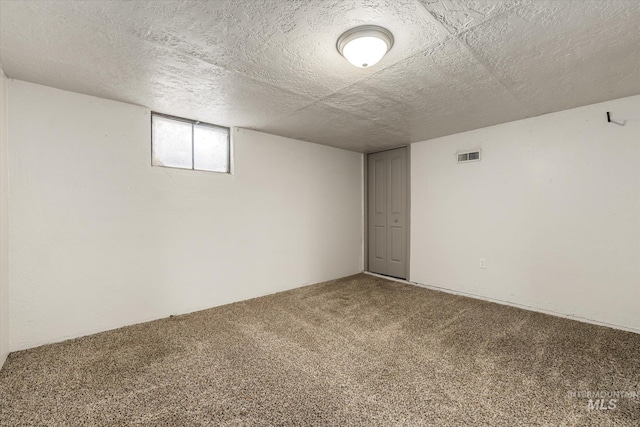 below grade area featuring visible vents, a textured ceiling, and carpet floors
