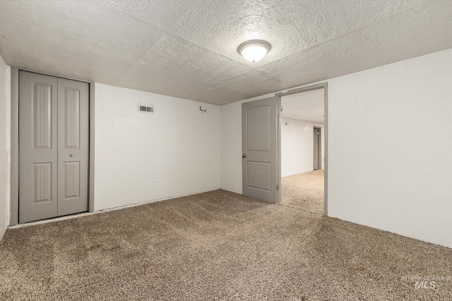 unfurnished bedroom with carpet floors, a textured ceiling, visible vents, and a closet
