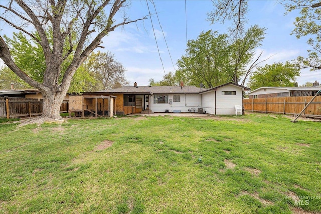 rear view of house with a chimney, cooling unit, a fenced backyard, a yard, and a patio